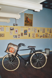 879162 Afbeelding van een transportfiets met op de drager een groot koffieblik van Douwe Egberts, op de begane grond ...